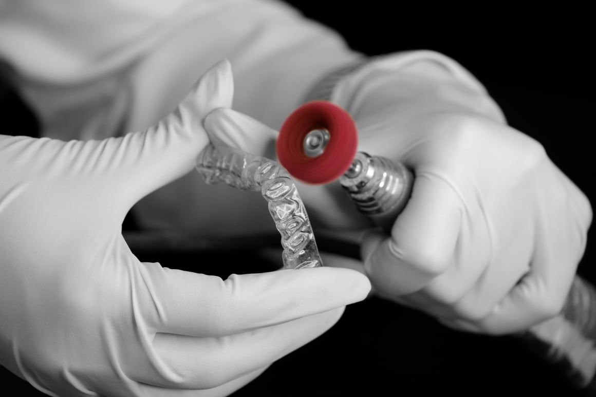 Hands buffing an invisible aligner